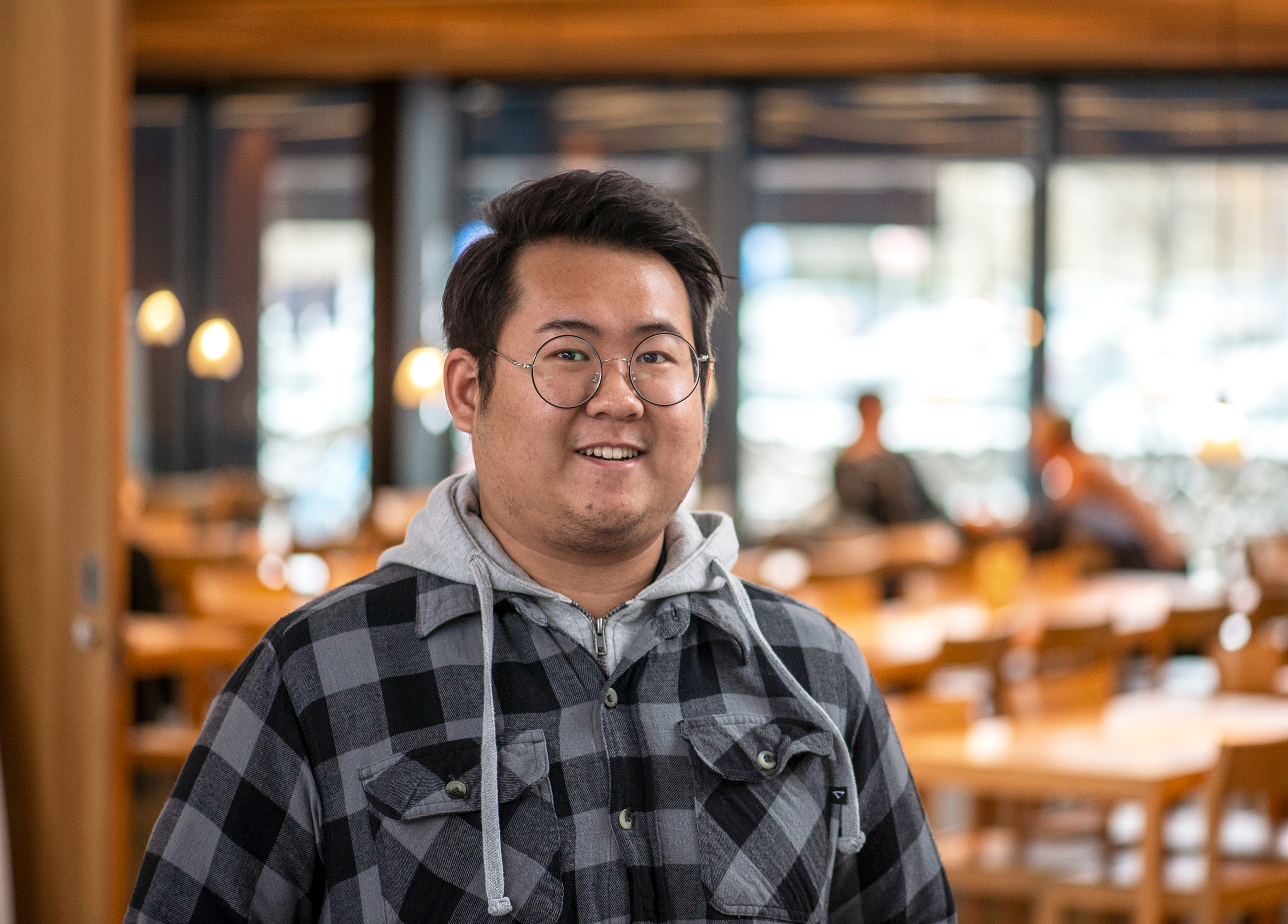 Young man smiling at the camera, cafeteria on the background.