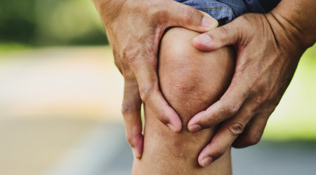 Man holding an aching knee.