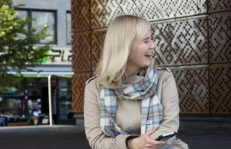 Opiskelija selaa puhelinta ja nauraa