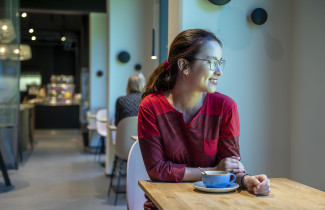 Young woman sitting at a cafe, smiling.