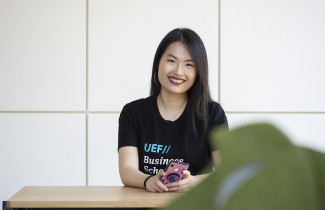 Young woman sitting, holding a mobile phone, smiling.