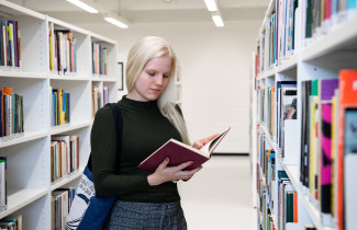 Naispuolinen opiskelija lukee kirjaa UEFin kirjastossa.