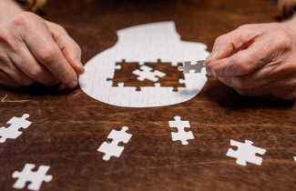 Kädet kokoamassa palapeliä.