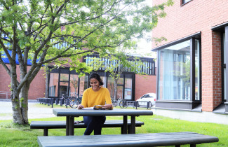 Nainen lukemassa rakennusten edustalla.