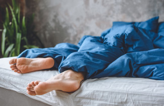 Nukkuvan henkilön jalat pilkistävät peiton alta