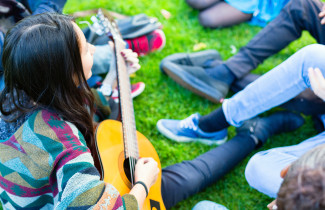 Young people playing guitar and singing.