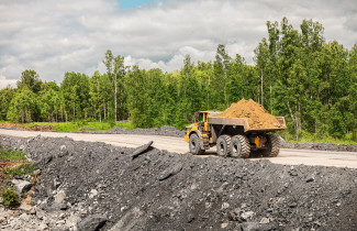 Kuorma-auto kuljettaa tiellä hiekkakuormaa.