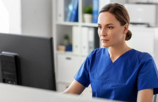 Sairaanhoitaja työskentelee tietokoneella.