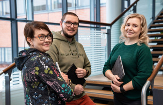 Kolme henkilöä seisoo ikkunan edessä.