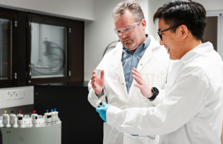 Kaksi tutkijaa keskustelee kemian laboratoriossa.