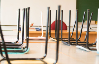 Oppilaiden penkit nostettu pöydille tyhjässä luokassa. 