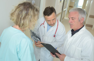 Lääkärit ja hoitaja katsovat kansiota.