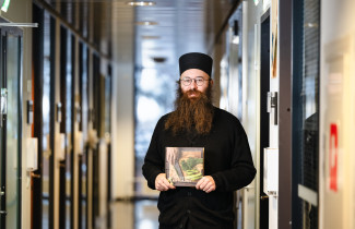 Damaskinos Olkinuora pitelee kirjoittamaansa keittokirjaa.