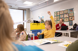 Alakoulun oppilas viittaa tunnilla.