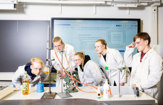 Ryhmä oppilaita tekee laboratoriokoetta luokassa.