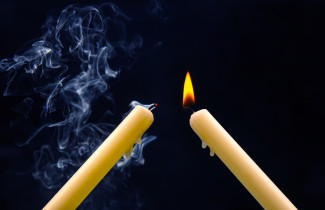 Kaksi kynttilää josta toinen on juuri sammunut.