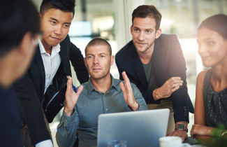 Ryhmä ihmisiä kannettavan tietokoneen ympärillä.