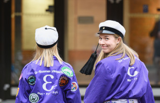 Kaksi teekkarihaalarista opiskelijaa kävelee kohti kampusta.