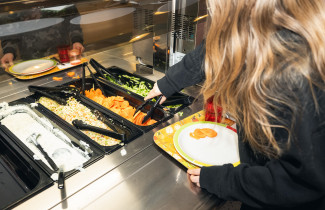 Oppilas ottamassa ruokaa koulun ruokalassa.