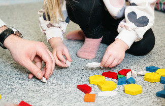 Lapsi leikkii alakoululla aikuisen kanssa.