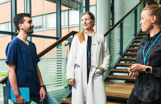 Lääkäri, hoitaja ja henkilökunnan jäsen rappusissa juttelemassa.