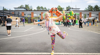 Hymyilevä tyttö koulun edessä.