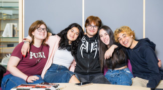 Ryhmä oppilaita hymyilee kameralle pöydän takana.