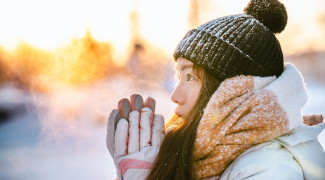 Student in winter outside with warm clothes, sun is shining