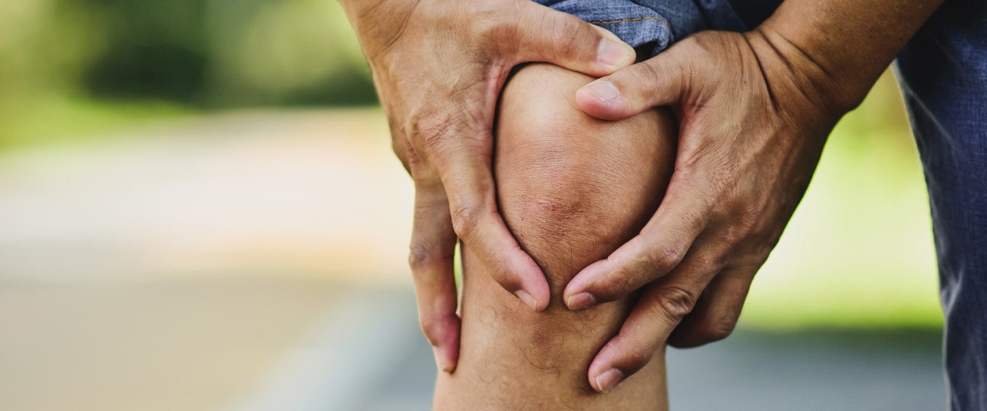 Man holding an aching knee.