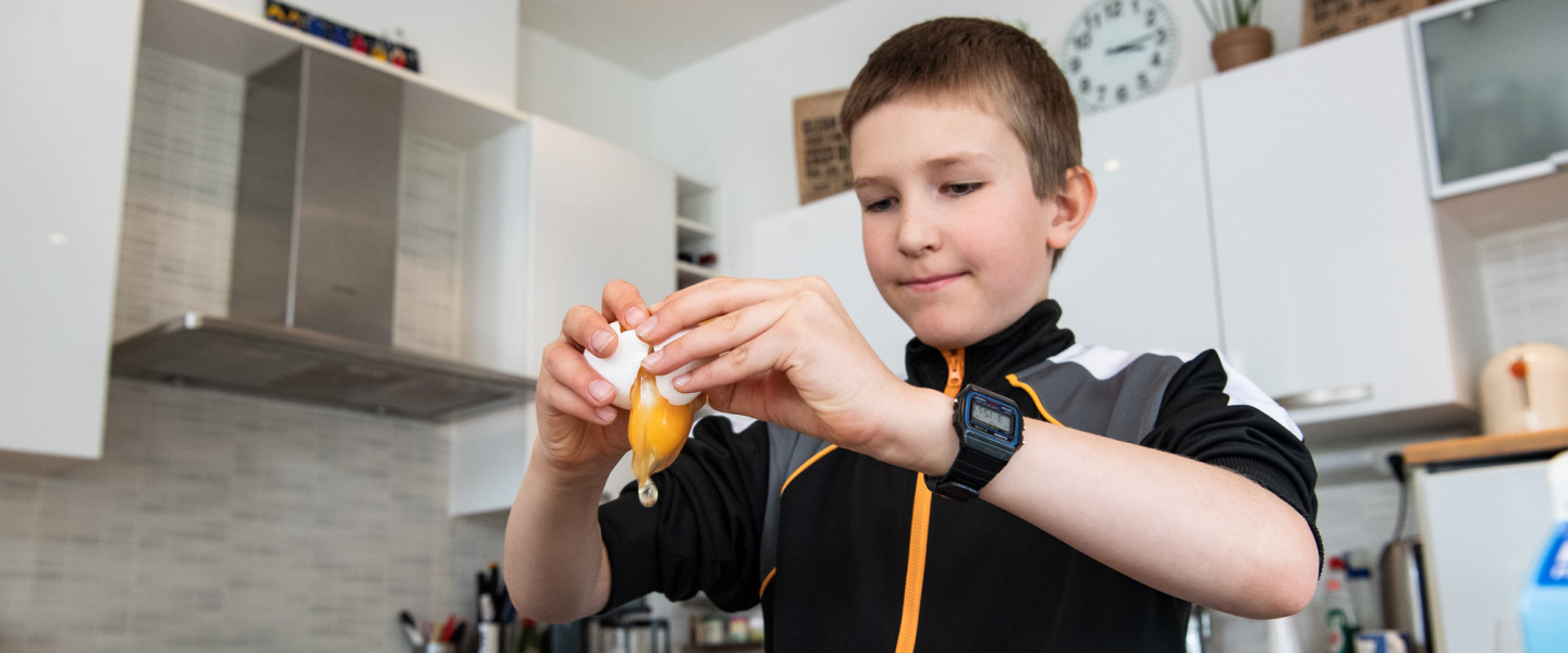 Boy cracking an egg.