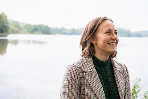 Young woman smiling, lake view behid her.