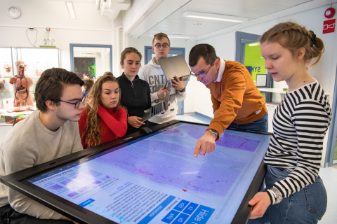 Teacher showing students a virtual sample on a touch screen.