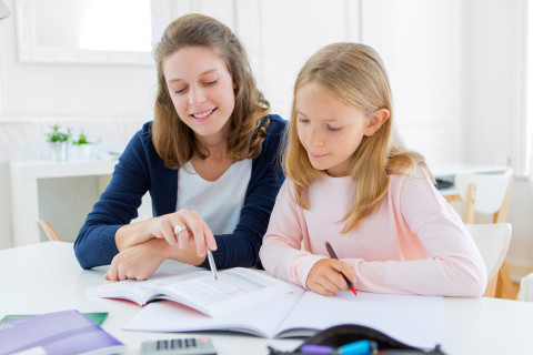 Äiti neuvoo lasta läksyissä.