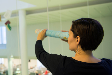 Nainen tähystää kaukaisuuteen rullattu kartta kaukoputkenaan.