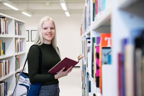 Naispuolinen opiskelija lukee kirjaa UEFin kirjastossa.