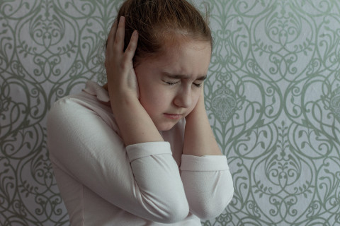 A girl covers her ears