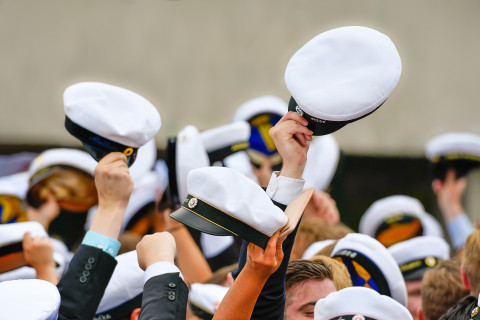 Opiskelijat heiluttavat ylioppilaslakkejaan.