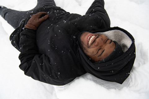 Man lying in snow and laughing