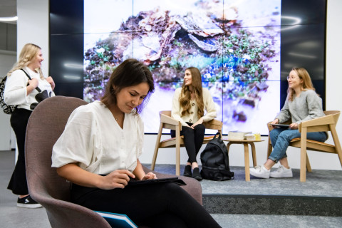 Neljä naisopiskelijaa istuu yliopiston oleskelutiloissa.