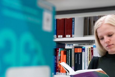 UEF-lähettiläs Mirka Nieminen kirjastossa selaamassa kirjaa