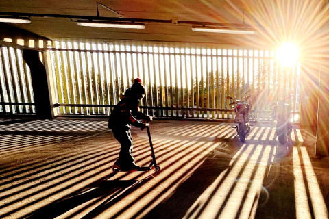 Lapsi potkulautailee parkkihallissa.