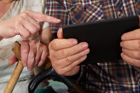 Kahden vanhan ihmisen kädet ja tablet-tietokone.