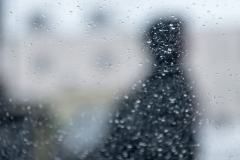 Hahmo sadepisaraisen ikkunan takana.