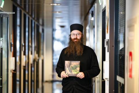 Damaskinos Olkinuora pitelee kirjoittamaansa keittokirjaa.