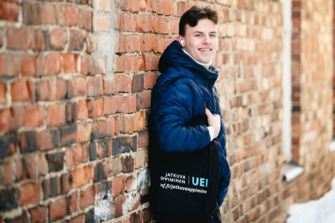 opiskelija nojaa tiiliseinään