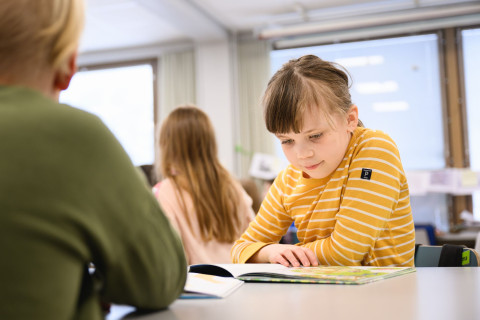 Tyttö lukee kirjaa oppitunnilla.