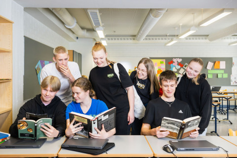 Ryhmä oppilaita tutkii kirjoja yhdessä.