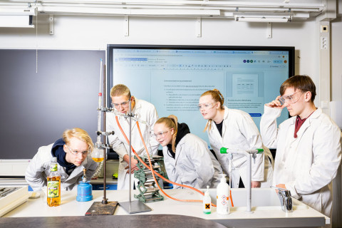 Ryhmä oppilaita tekee laboratoriokoetta luokassa.