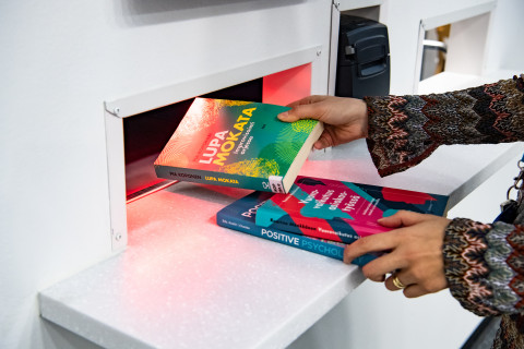 Palautusluukku, kaksi kirjaa, kädet.