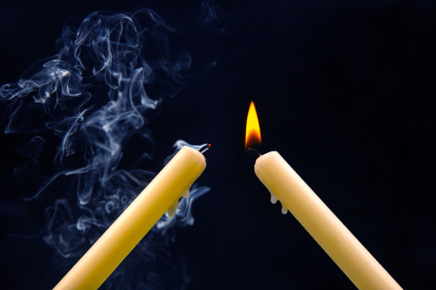 Kaksi kynttilää josta toinen on juuri sammunut.